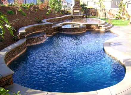 A pool with a waterfall and a stone wall.