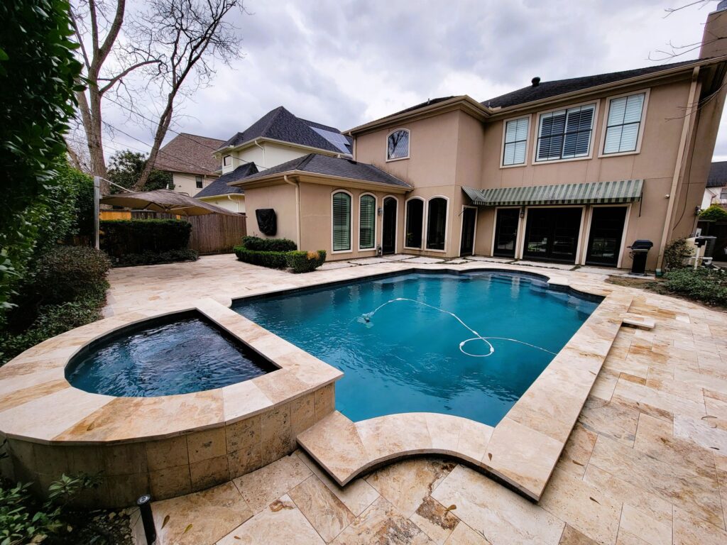 Remodeled swimming pool featuring Stone Scapes mini pebble plaster, glass tile, and travertine coping and deck in Houston, Texas.